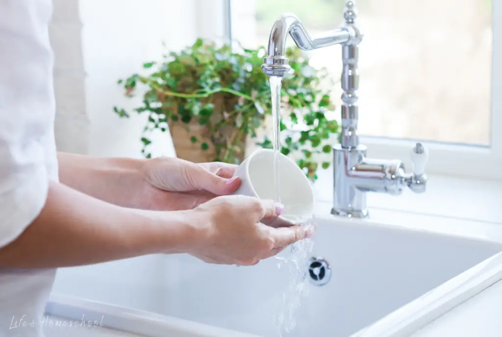 Hands washing white coffee mug as part of the Mothers day idea to clean up after cooking